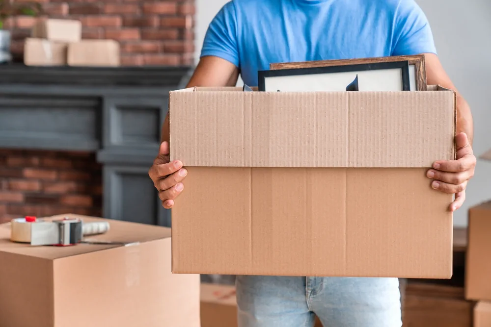 Mann trägt vollgepackten Umzugskarton